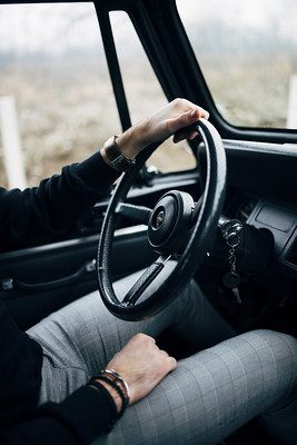 A fashionable man behind a steering wheel